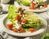 Eisbergsalat-Rezept: knackige Salatspalten mit cremiger Blauschimmelkäse-Dressing, Speck und Tomaten.