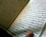 Ein Finger zeigt auf eine Seite des Korans. Die Frage, wer hat den Koran geschrieben, wird durch die heiligen Schriften beantwortet.