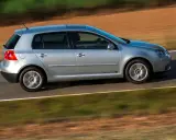 Srebrny Golf 5 1.9 TDI w ruchu, z rozmytym tłem pól i zieleni.