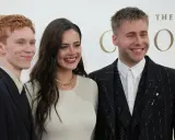 Skådespelare från "The Crown" ler glatt. En man med rött hår i mörk kavaj, en kvinna i ljus tröja och en man i mönstrad kavaj.