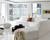 Soggiorno minimalista con divano bianco curvo, sedie futuristiche e tavolini geometrici, un vero esempio di space age design.