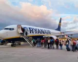 Samolot Ryanair z pasażerami wchodzącymi po schodach na pokład.