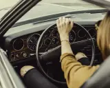Mujer al volante de un coche clásico. De repente, la dirección asistida dura, dificultando el giro.