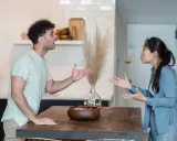 Pareja discutiendo en la cocina, un momento de reflexiones de pareja en crisis. Sus gestos y expresiones muestran tensión.