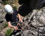 Mężczyzna w kasku przygotowuje się do wspinaczki dla początkujących, sprawdzając sprzęt na skalnej ścianie.