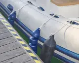 Un bateau pneumatique est amarré à un quai, avec des pare-battages bleus et noirs prêts à gonfler pour protéger la coque.