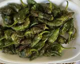 Pimientos de Padrón recién fritos, salpicados de sal gruesa, listos para disfrutar. ¡Así se preparan como freir pimientos de padron!