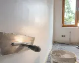 Idealna ściana po gładzi jest gładka i równa. Na zdjęciu widać narzędzie do jej wygładzania.