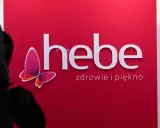 Logo Hebe z motylem na czerwonym tle.