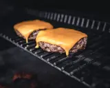Zwei saftige Burger-Patties auf dem Grill, mit leckerem cheddar schmelzen, der langsam heruntertropft.