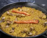 Paella de arroz con carne, pimientos rojos y caracoles. Un plato tradicional español lleno de sabor.