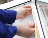Ręce montują uszczelnienie parapetu wewnętrznego, zapewniając szczelność okna.