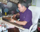 Un artisan ajuste les cordes d'un kanun, instrument de musique traditionnel, avec un marteau.