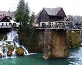 Rastoke, Croazia: cascate e mulini sull'acqua. Un ponte metallico attraversa il fiume, collegando case tradizionali.