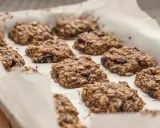 Na blasze wyłożonej papierem do pieczenia leżą świeżo upieczone, zdrowe ciasteczka owsiane z bakaliami. Idealne do kawy, jako przekąska lub element przepisu na zdrowe ciasteczka.