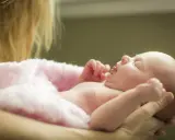 Nowa istota, jak bogini z mitologii, z imionami żeńskimi w tle, otulona różowym kocykiem.
