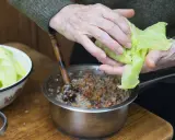 Ręce zwijają gołąbka, w garnku farsz z kaszą i warzywami. Zastanawiasz się, jakie przyprawy do farszu na gołąbki?
