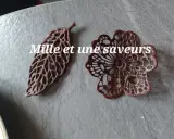 Délicates décorations en chocolat, une feuille et une fleur, réalisées avec une pâte à cigarette fine.