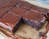Saftige, vegane Brownies mit glänzendem Schokoladenguss, auf Backpapier zugeschnitten. Ein Traum für jeden Schokoladenliebhaber!