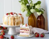 Eine köstliche Erdbeer Baiser Torte mit frischen Erdbeeren und zartem Baiser. Ein Stück der Torte zeigt die saftigen Schichten.