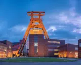 Industrielles Erbe: Der Förderturm des Zollverein 1834 ragt über die beleuchteten Backsteingebäude.