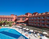 Słoneczny dzień w club side coast. Basen z wodnymi zjeżdżalniami, leżaki i palmy przy hotelu.
