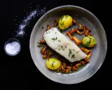 Ein köstliches Heilbutt-Rezept: zartes Fischfilet mit kleinen Kartoffeln und Pfifferlingen, garniert mit frischen Kräutern.