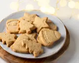 Assortiment de sablés de Noël en forme de sapins, étoiles et cloches, parfaits pour accompagner un chocolat chaud.