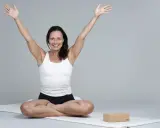 Kvinna i meditationsställning med armarna uppåt, utstrålar lugn och glädje. Hon praktiserar metta meditation för inre frid.