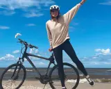 Dziewczyna w kasku na rowerze na plaży. Wspaniała infrastruktura rowerowa nad morzem.