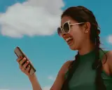 Uśmiechnięta dziewczyna w okularach trzyma telefon, słuchając muzyki. Kto to śpiewa?