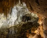 Wnętrze jaskini w Dolinie Kościeliskiej, pełne stalaktytów i stalagmitów. Kamieniste dno i skalne ściany tworzą tajemniczy krajobraz.