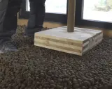 Preparando el suelo para como hacer hormigón con arlita. Se ve una capa de arlita y una base de madera.