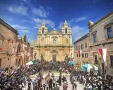 Tłum ludzi w historycznych strojach zgromadzony na placu przed katedrą w Mdina, Malta.