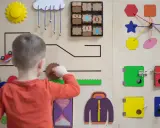 Chłopiec bawi się na tablicy edukacyjnej, rozwijając zdolności manualne. To świetna metoda montessori dla małych odkrywców.