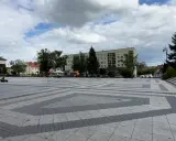 Dziecko na gokarcie przemierza pusty plac, który może być największym rynkiem w Polsce. W tle budynki mieszkalne i drzewa.