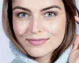 Visage de femme au regard intense, mettant en valeur ses sourcils parfaits. Elle porte un pull bleu ciel.