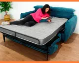Mujer relajada en un sofá cama abierto, usando su tablet. Los sofabeds son perfectos para ahorrar espacio.
