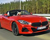 Czerwone z4 bmw z opuszczonym dachem pędzi po drodze, kierowca w czapce z daszkiem cieszy się jazdą.