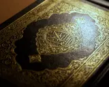 Ein prachtvoller Koran mit goldener Verzierung. Die Mitte ziert eine kunstvolle Kalligraphie, die an die Weisheit der **Surah Luqman** erinnert.
