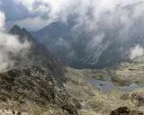 Widok na Tatry z chmurami. Szlak turystyczny prowadzi przez kamieniste zbocza do stawów. Idealne miejsce na **rysy dla początkujących**.