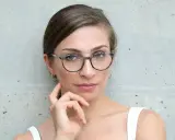 Eleganckie okulary dla szczupłej twarzy podkreślają spojrzenie kobiety.