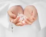 Dłonie trzymające różaniec, symbol modlitwy i intencje papieskie.