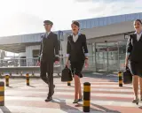 Pilot i dwie stewardessy idą przez pasy na lotnisku w Czarnogórze.