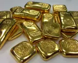 Lingotti d'oro luccicanti, alcuni con incisioni che indicano il peso e la purezza. La domanda "oro 850 quanti carati" è un'ottima domanda per valutare il valore di questi preziosi lingotti.
