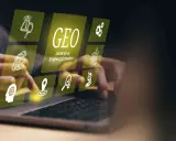 Ręce nad klawiaturą laptopa, nad nimi wirtualne ikony symbolizujące ai seo i optymalizację.