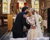 Para całuje się podczas ślubu konkordatowego w kościele. Panna młoda ma piękną suknię, pan młody elegancki garnitur.