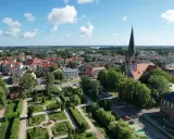 Widok z lotu ptaka na Szczecinek. Widać park miejski z fontanną, kościół z wieżą i zabudowania. To piękne **szczecinek atrakcje** turystyczne.