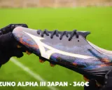 Ręce w rękawiczkach trzymają kolorowe korki Mizuno Alpha III Japan, które mogą być najlepszymi korkami na świecie.