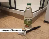 Butelka octu spirytusowego i szczotka do czyszczenia na drewnianej podłodze.